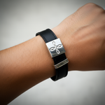 Black leather bracelet with a silver clasp on a wrist against a gray background